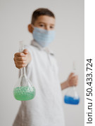 boy with face mask holding chemical elements recipients. Стоковое фото, агентство Ingram Publishing / Фотобанк Лори