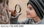 side view little boy looking through magnifier. Стоковое фото, агентство Ingram Publishing / Фотобанк Лори