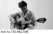 A man in casual clothing sits on a chair, playing a guitar with concentration and skill. Стоковое AI-изображение, AI-художник Данила Большаков / Фотобанк Лори