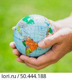 hands holding small globe against green background. Стоковое фото, агентство Ingram Publishing / Фотобанк Лори