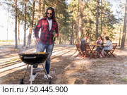 man roasting corn barbecue while friends converse table. Стоковое фото, агентство Ingram Publishing / Фотобанк Лори