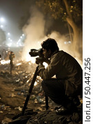 A man in action taking a picture of a fire with a camera. Стоковое AI-изображение, AI-художник Данила Большаков / Фотобанк Лори