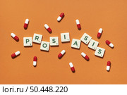 Psoriasis word formed of scrabble blocks and pharmaceutical pills strewn over orange backdrop. Skin disease and medical treatment concept.. Psoriasis formed of scrabble blocks and pharmaceutical pills. Стоковое фото, агентство Ingram Publishing / Фотобанк Лори