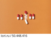 Pharmaceutical capsules neatly laid with medication powder over orange background, top view.. Pharmaceutical capsules with medication powder. Стоковое фото, агентство Ingram Publishing / Фотобанк Лори