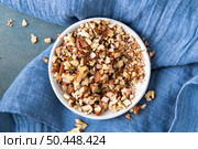 Small white ceramic bowl with crushed pecan nuts on blue cloth background. Top view. Стоковое фото, агентство Ingram Publishing / Фотобанк Лори