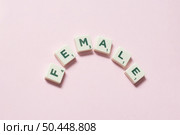 Female word formed of scrabble tiles on pink background. Social awareness and education concept.. Female formed of scrabble tiles on pink background. Стоковое фото, агентство Ingram Publishing / Фотобанк Лори