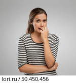 Nervous woman bitting nails over a gray background. Стоковое фото, агентство Ingram Publishing / Фотобанк Лори