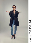 Beautiful and confident young  woman against a gray background showing her hands. Стоковое фото, агентство Ingram Publishing / Фотобанк Лори