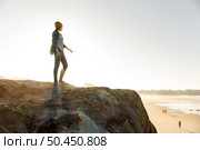 Beautiful woman with a yellow cap and walking over the cliff to see the beach. Стоковое фото, агентство Ingram Publishing / Фотобанк Лори