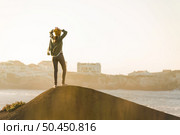 Beautiful woman with yellow cap over the cliff seeing the beach. Стоковое фото, агентство Ingram Publishing / Фотобанк Лори