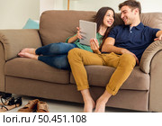 Young couple sitting on the sofa and watching something on a tablet. Стоковое фото, агентство Ingram Publishing / Фотобанк Лори