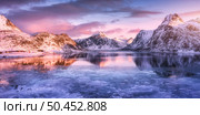 Aerial view of snowy rocky mountains, blue sea with frosty coast, reflection in water, sky with pink clouds at sunset. Lofoten islands, Norway. Winter landscape with snow covered rocks, fjord, ice. Стоковое фото, агентство Ingram Publishing / Фотобанк Лори