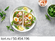 Toast with shrimps, avocado guacomole, arugula and boiled egg, top view. Стоковое фото, агентство Ingram Publishing / Фотобанк Лори