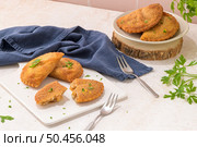 Meat patties and parsley leaves on white ceramic dishes in a kitchen counter top. Стоковое фото, агентство Ingram Publishing / Фотобанк Лори