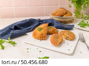 Meat patties and parsley leaves on white ceramic dishes in a kitchen counter top. Стоковое фото, агентство Ingram Publishing / Фотобанк Лори