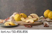 Ripe yellow quinces or queen apple fruits and sliced quince halves with seeds in craft cork plates on black rustic background. Стоковое фото, агентство Ingram Publishing / Фотобанк Лори