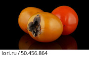 Red ripe persimmons rotating over black background. Стоковое фото, агентство Ingram Publishing / Фотобанк Лори