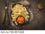 Farfalle pasta in a ceramic plate with pumpkin puree and pine nuts in a small ceramic bowl on a dark stone kitchen counter top. Стоковое фото, агентство Ingram Publishing / Фотобанк Лори