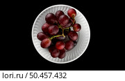 Top view of grapes with water drops in white plate rotating on black background. Стоковое фото, агентство Ingram Publishing / Фотобанк Лори