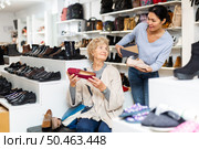 Friendly female sales consultant serves a mature woman who is going to try on shoes. Стоковое фото, фотограф Яков Филимонов / Фотобанк Лори