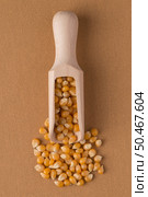 Top view of wooden scoop with corn against brown vinyl background. Стоковое фото, агентство Ingram Publishing / Фотобанк Лори