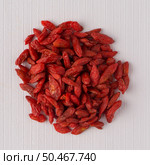 Top view of circle of dry red goji berries against white vinyl background. Стоковое фото, агентство Ingram Publishing / Фотобанк Лори