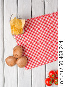 Wooden kitchen table with red towel, tomatos, potatoes and fries. Стоковое фото, агентство Ingram Publishing / Фотобанк Лори