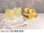 Cold lemonade or alcoholic cocktail with lemon, rosemary and ice in glass glasses on a light background. Стоковое фото, агентство Ingram Publishing / Фотобанк Лори
