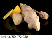 Ginger root drizzler with honey and lemon on black reflective background. Concept of natural ingredients to prevent colds. Стоковое фото, агентство Ingram Publishing / Фотобанк Лори