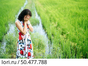 The woman stood strained and her hand closed her face in the meadow. Стоковое фото, агентство Ingram Publishing / Фотобанк Лори