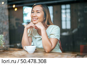 The woman is sitting in a coffee shop, putting the chin on the back of the hand and having a cup of coffee. Стоковое фото, агентство Ingram Publishing / Фотобанк Лори