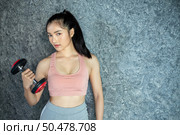 Woman standing exercising with a red dumbbell in the gym. Стоковое фото, агентство Ingram Publishing / Фотобанк Лори