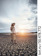 The woman stand his hand and caught a Siem on dry soil and looked at the sky. Стоковое фото, агентство Ingram Publishing / Фотобанк Лори