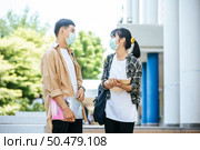 Male and female students wear a health mask and talk to each other on the stairs. Стоковое фото, агентство Ingram Publishing / Фотобанк Лори
