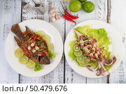 Tilapia fried with chilli sauce and squid, lemon and garlic on a plate on a white wooden table. Стоковое фото, агентство Ingram Publishing / Фотобанк Лори