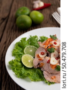 Spicy lime pork with salad, galangal, chilli, tomato and garlic on a white plate on a wooden floor. Стоковое фото, агентство Ingram Publishing / Фотобанк Лори