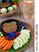 Chili paste paste in a bowl with eggplant, carrots, chili, cucumbers in a basket on wood table. Стоковое фото, агентство Ingram Publishing / Фотобанк Лори