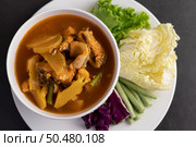 Yellow curry with snakehead fish, Thai food in a bowl on a plate with yard long bean, fried white cabbage, salad and purple cabbage. Стоковое фото, агентство Ingram Publishing / Фотобанк Лори