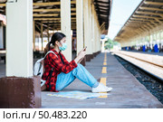 Tourists sitting and watching phones on the footpath beside the railway. Стоковое фото, агентство Ingram Publishing / Фотобанк Лори