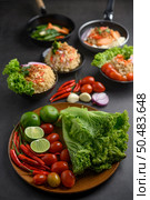 Lemon slices, shallots, garlic, tomatoes, lettuce and peppers on a wooden plate on a black cement floor. Selective focus. Стоковое фото, агентство Ingram Publishing / Фотобанк Лори
