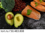 Legumes, broccoli, fruit, and salmon placed on a black cement floor. Top view. Стоковое фото, агентство Ingram Publishing / Фотобанк Лори