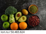 Broccoli, Apple, orange, kiwi, Red bean, Mung bean and avocado on a black cement floor background. Стоковое фото, агентство Ingram Publishing / Фотобанк Лори