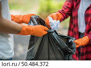Men and women helped to collect garbage in a black bag. Стоковое фото, агентство Ingram Publishing / Фотобанк Лори