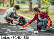 Men and women helped to collect garbage in a black bag. Стоковое фото, агентство Ingram Publishing / Фотобанк Лори