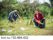 Men and women helped to collect garbage in a black bag. Стоковое фото, агентство Ingram Publishing / Фотобанк Лори
