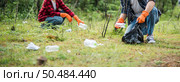 Men and women helped to collect garbage in a black bag. Стоковое фото, агентство Ingram Publishing / Фотобанк Лори