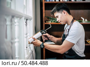 The carpenter holds the glue and attaches to the window. Selective focus. Стоковое фото, агентство Ingram Publishing / Фотобанк Лори