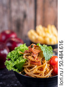 Spaghetti in a black cup with tomatoes and lettuce. Selective focus. Стоковое фото, агентство Ingram Publishing / Фотобанк Лори