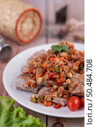 Spicy pork minced with tomatoes and lettuce on a white plate on a wooden table. Selective focus. Стоковое фото, агентство Ingram Publishing / Фотобанк Лори