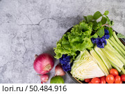 Shallots, peppers, lemons, tomatoes, cucumbers, long beans, cabbage, lettuce and mint in a bowl on the cement floor. Стоковое фото, агентство Ingram Publishing / Фотобанк Лори